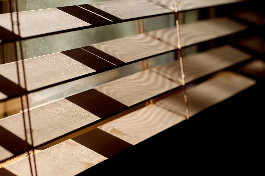 Afternoon light coming through partly open wooden window blinds in a room