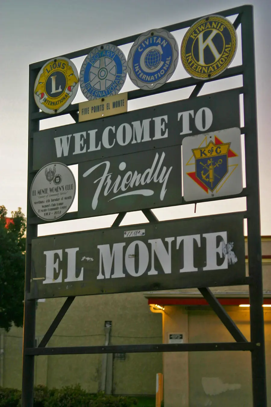 Friendly El Monte welcome sign with service club emblems near a street
