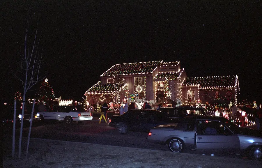 Houses at night outlined with white holiday lights along the rooflines