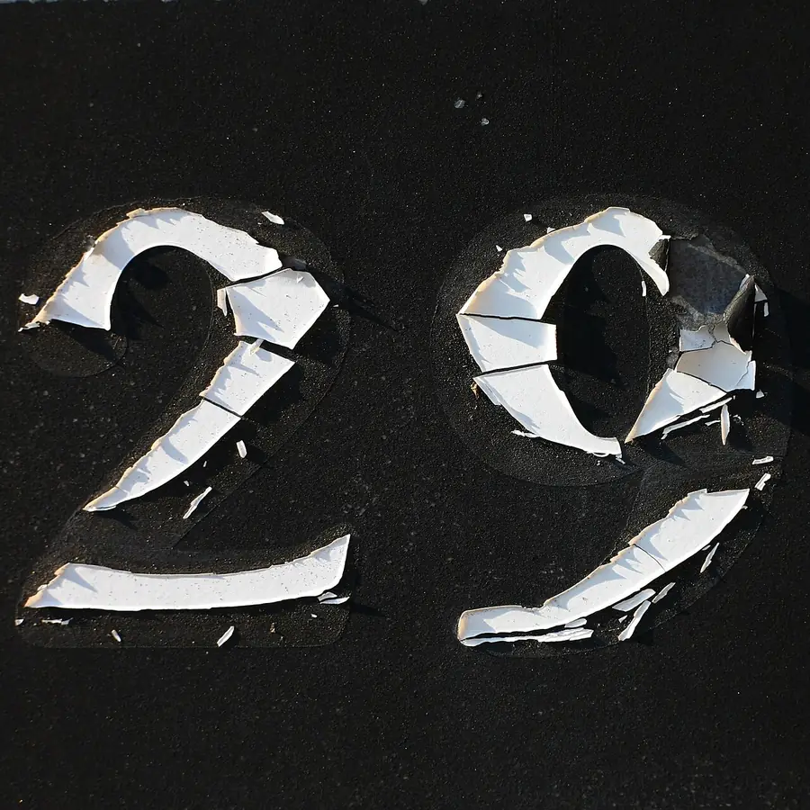 Large white painted house numbers on a black wall, close view