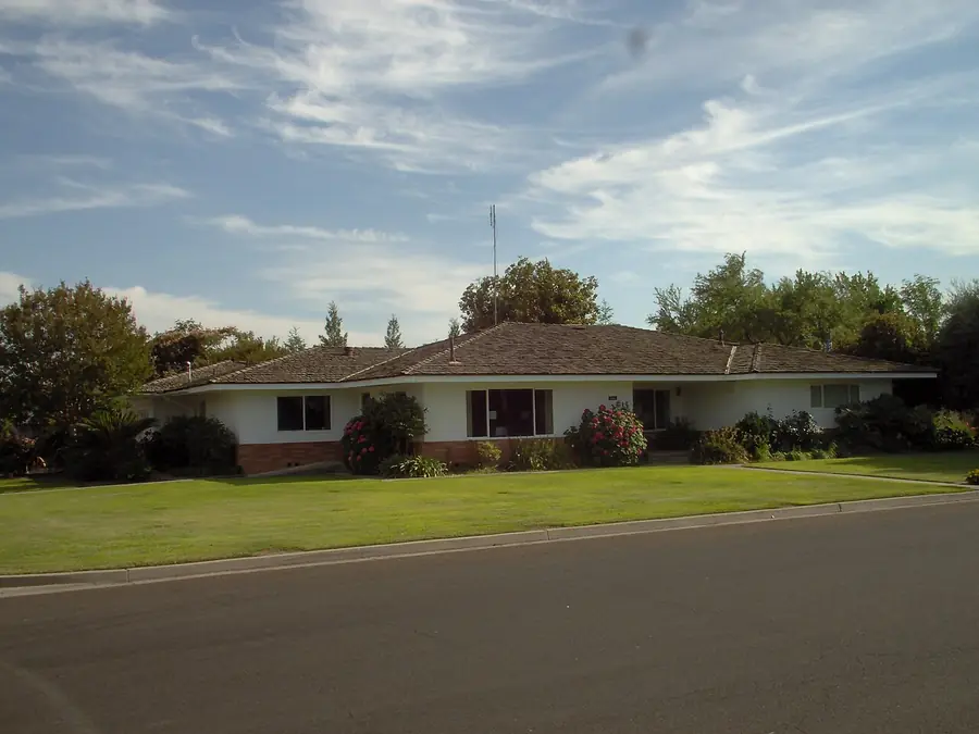 Single-story stucco ranch house with a green lawn on a California street