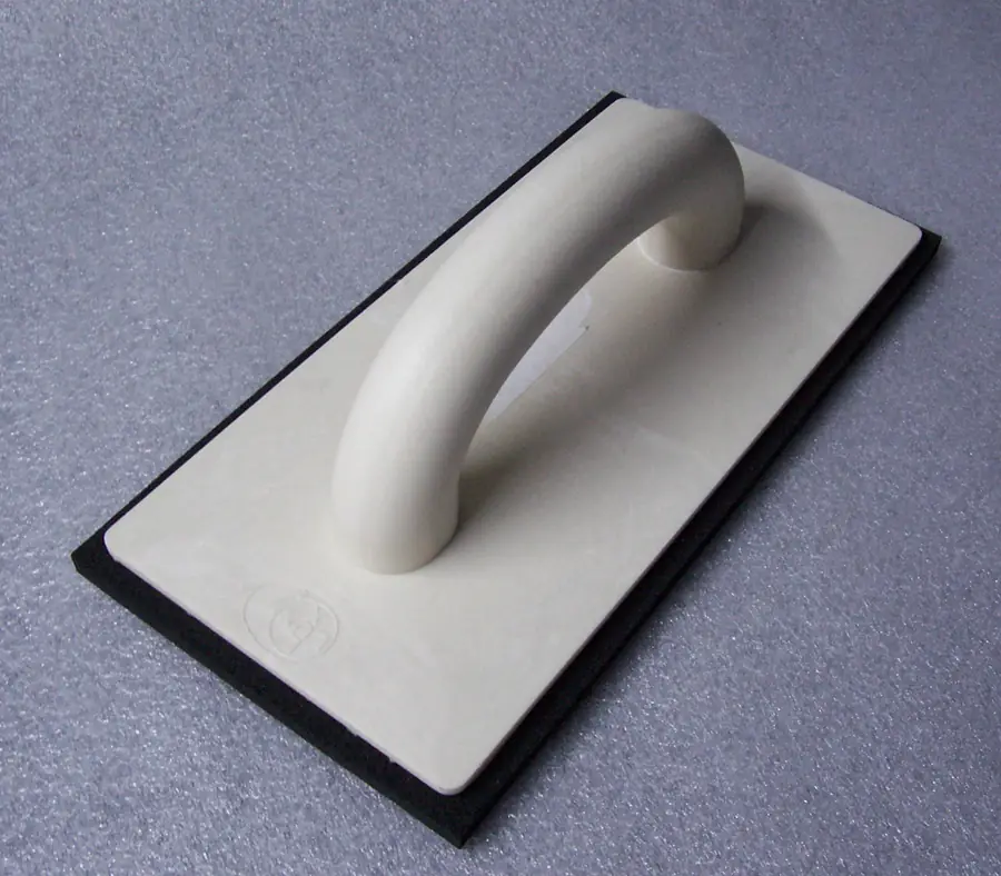 Rubber grout float with a curved handle used to press grout into tile joints