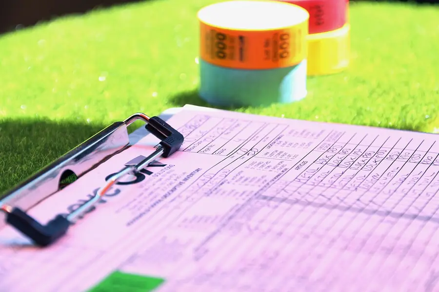 Pink move-in inventory checklist on a clipboard lying on green grass