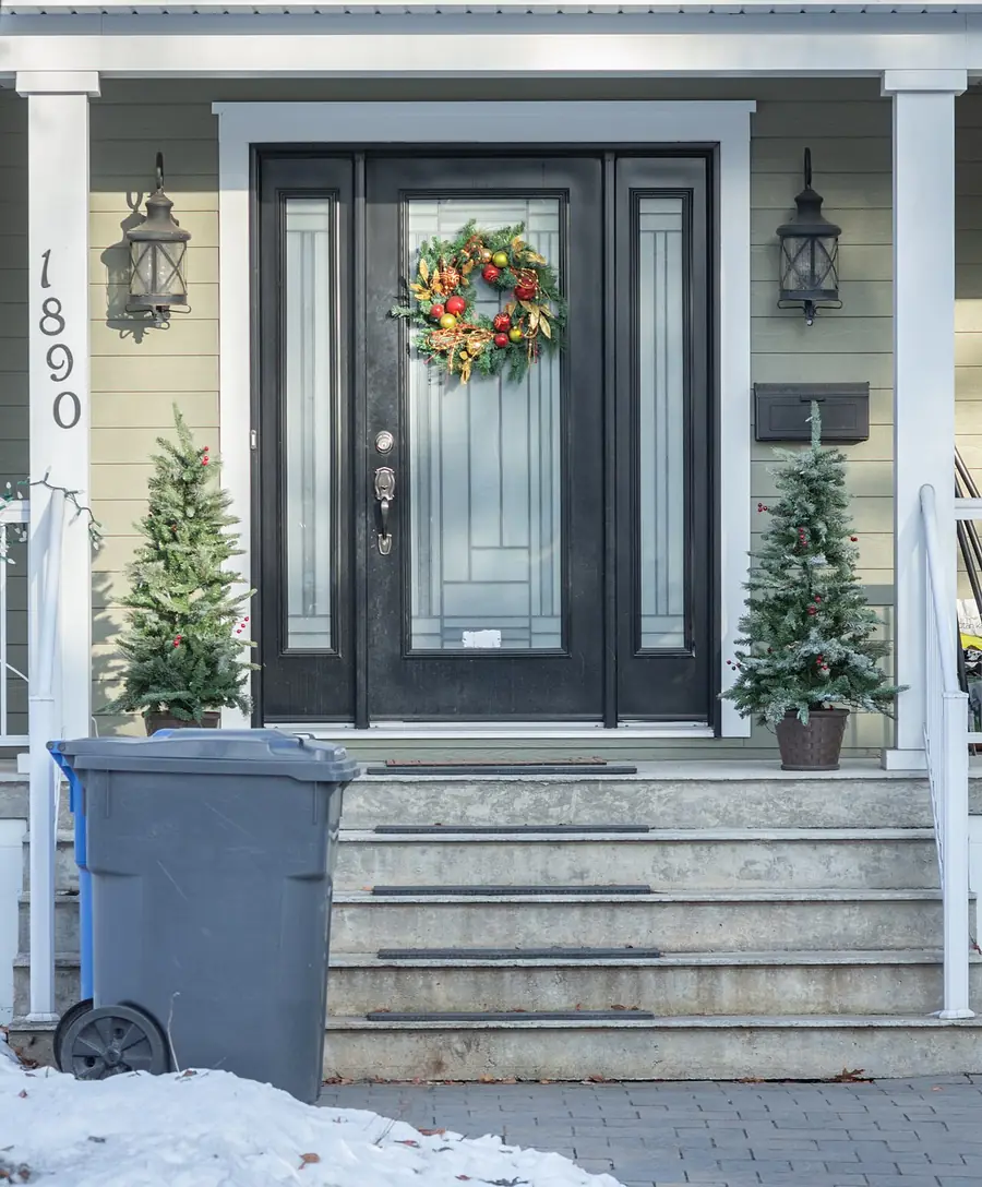 Dark front door with glass panels and a wreath at the top of stone steps