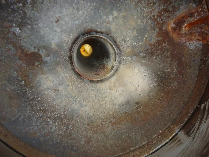 Flue pipe opening seen from below inside a disassembled tank water heater