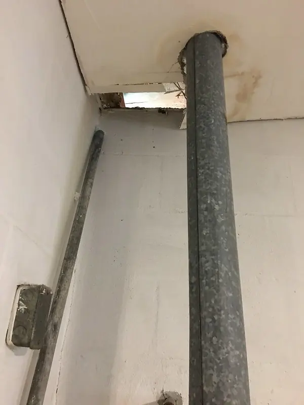 Metal water heater vent pipe rising through a hole in the ceiling