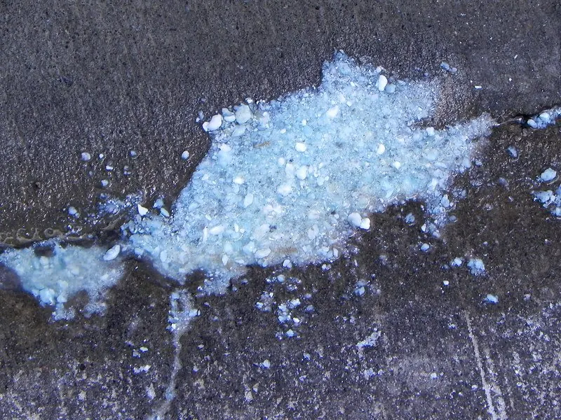 White mineral sediment flushed out of a water heater onto concrete