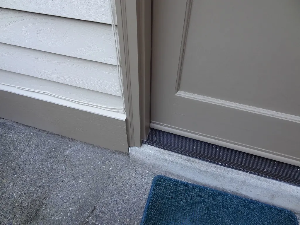 Gray exterior door with a new threshold and tight seal at the bottom