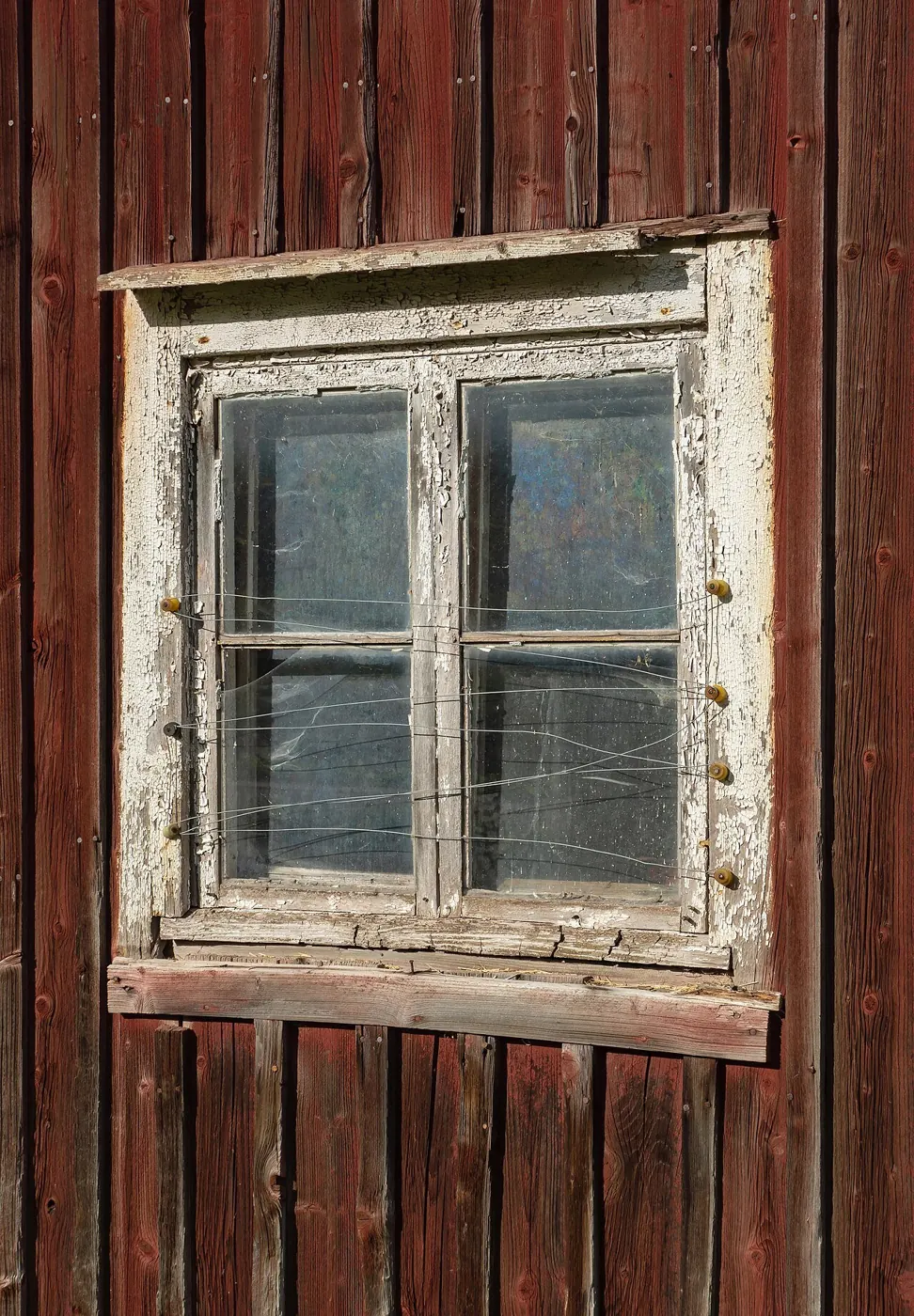 Old wooden window on a red barn wall