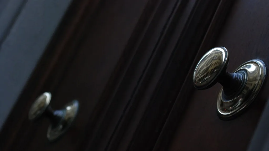 Two round metal knobs on a dark wooden door
