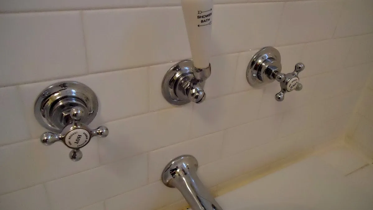 Chrome tub and shower valve handles on white tile