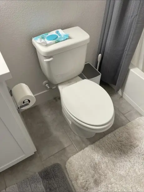 Two-piece white toilet in a small bathroom after a repair