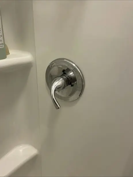 Single-lever shower valve handle on a white surround