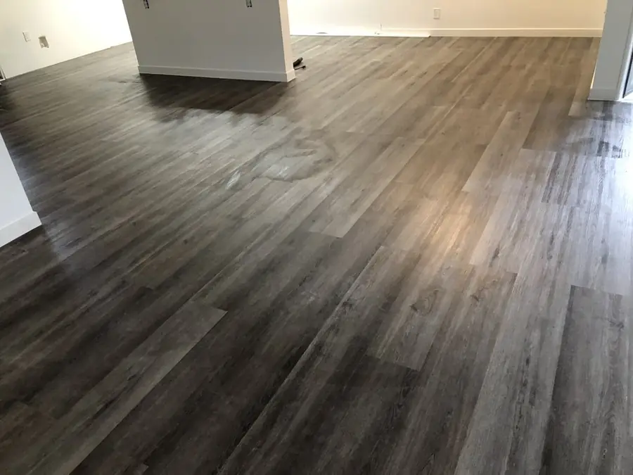 Empty bedroom with new gray plank flooring and white walls between tenants