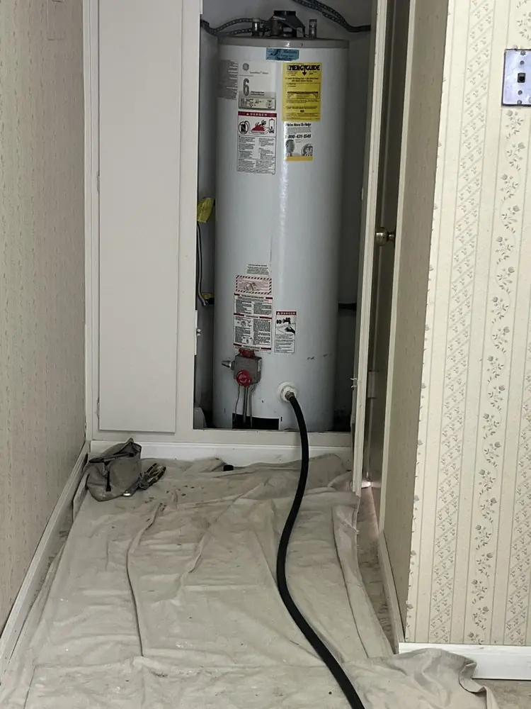 Gas tank water heater standing in a garage alcove after replacement